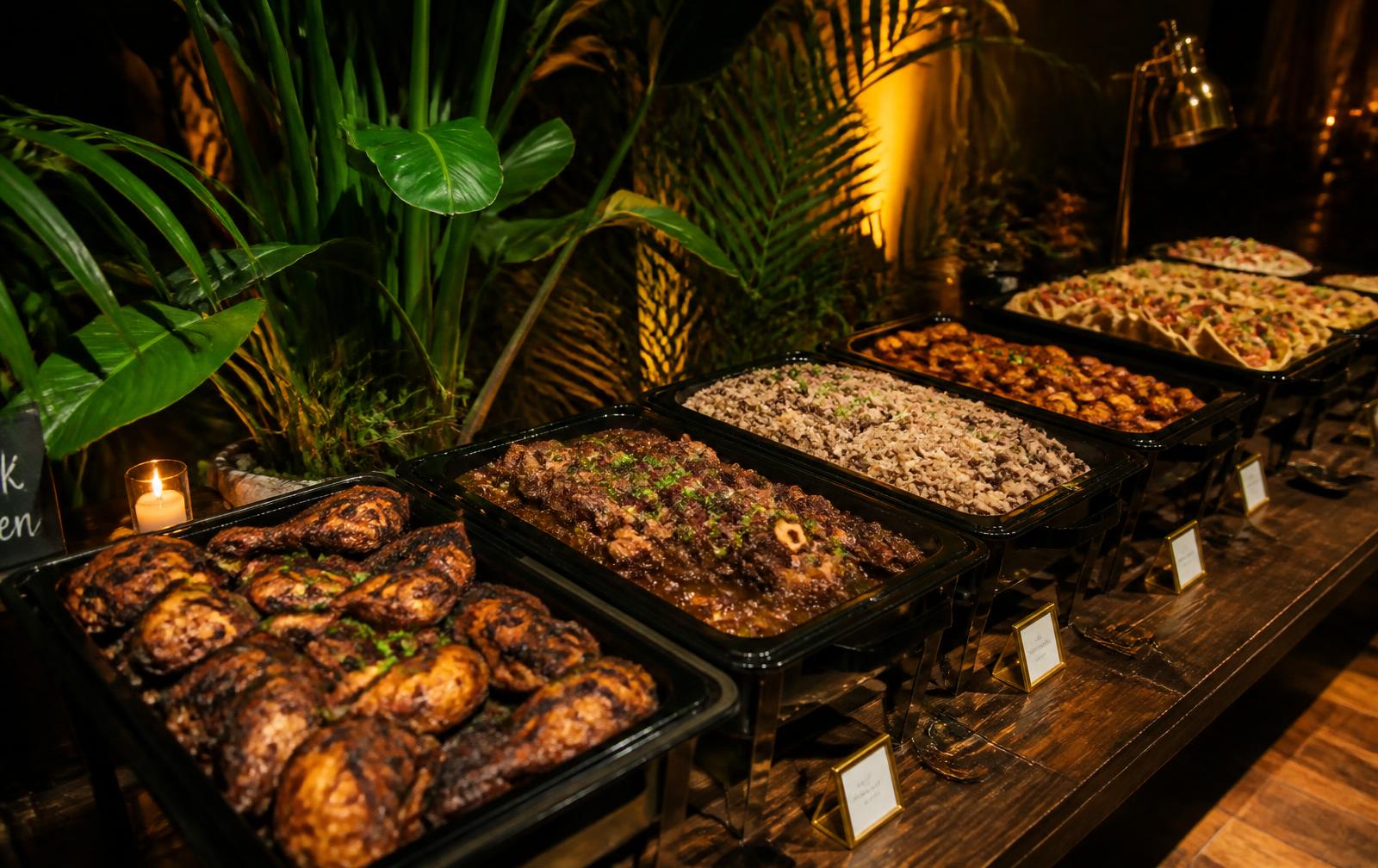 Caribbean catering spread of jerk chicken, oxtail and rice and peas